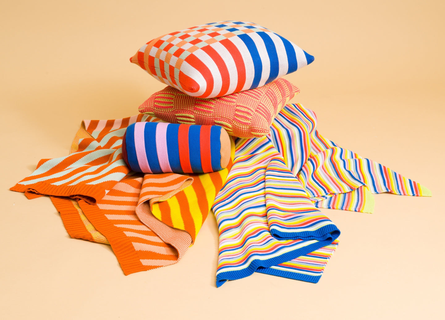 pile of colorful knit pillows and throws in graphic striped motifs