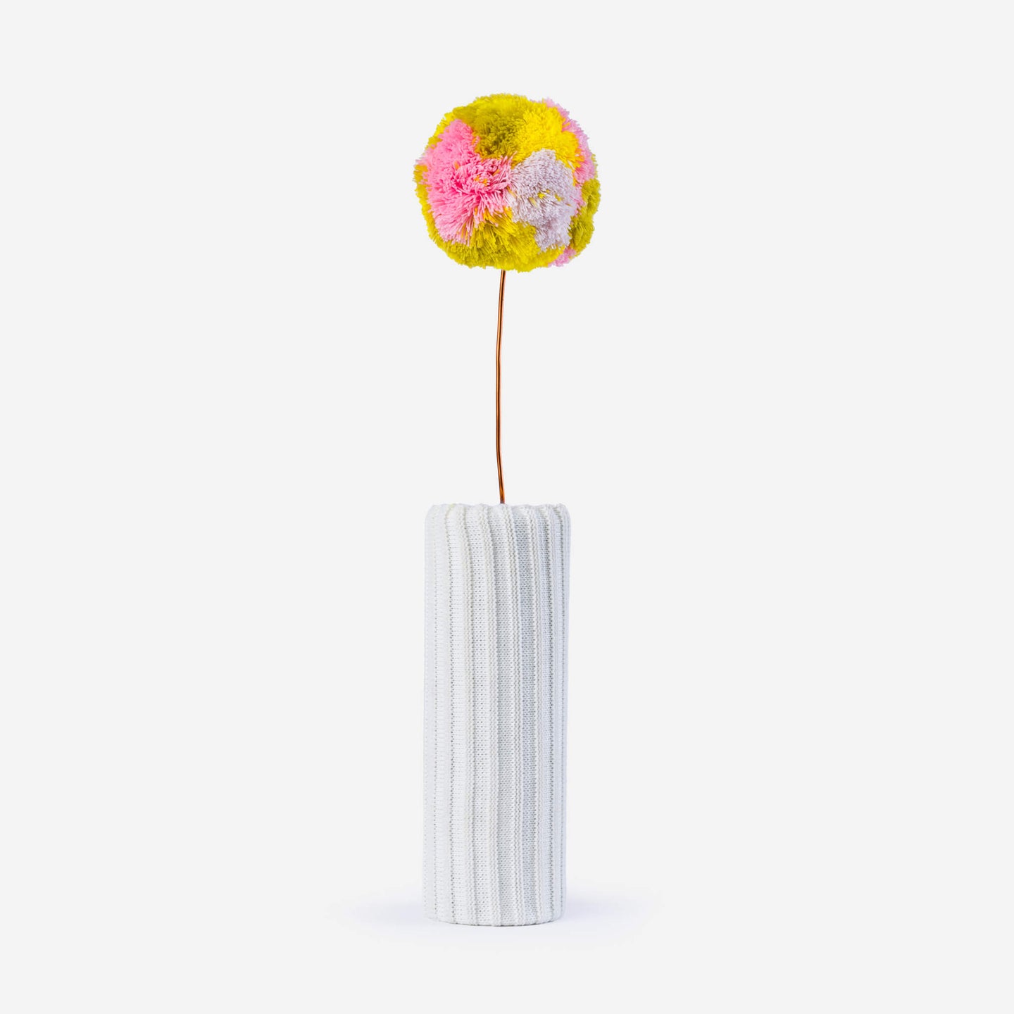 colored knitted pom pom on a wire with a white background