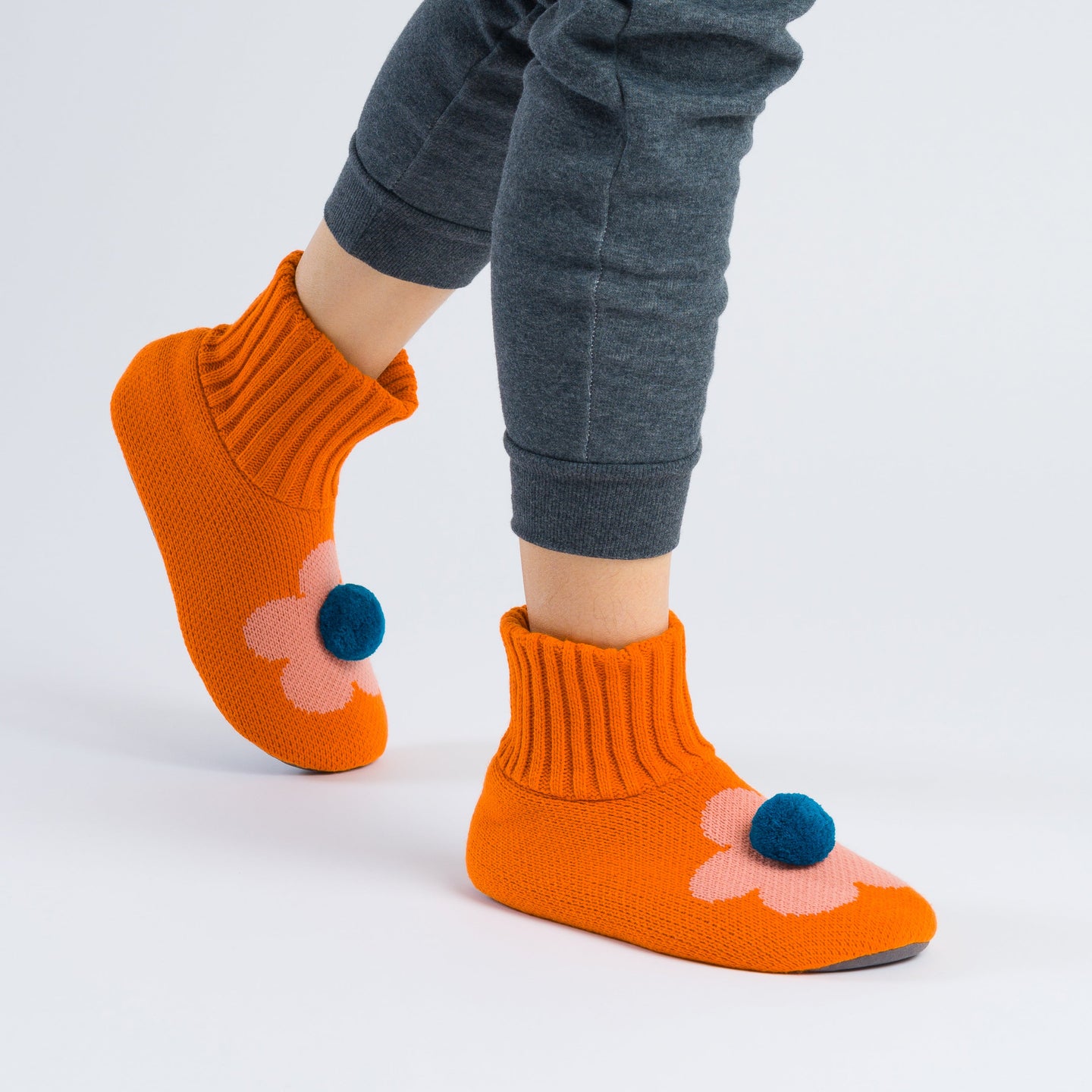 Orange non slip knit slippers with a pom on top walking