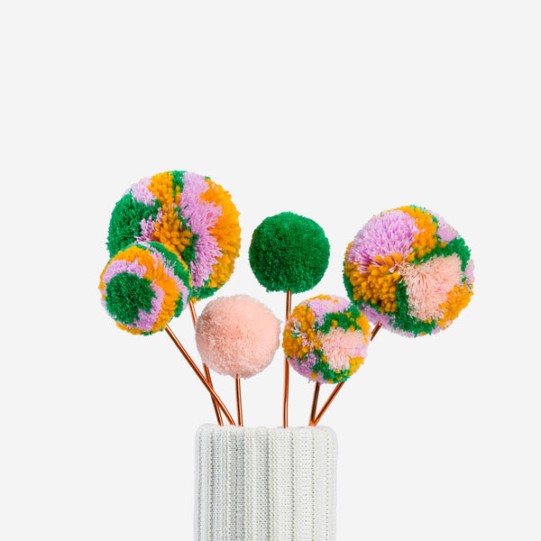 Kelly Peach | colored pom pom flower bouquet in a knitted vase with a white background