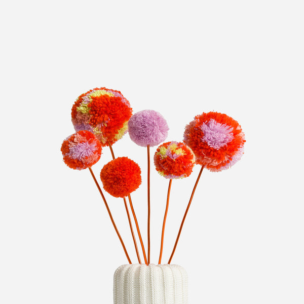 Poppy Lilac | colored pom pom flower bouquet in a knitted vase with a white background