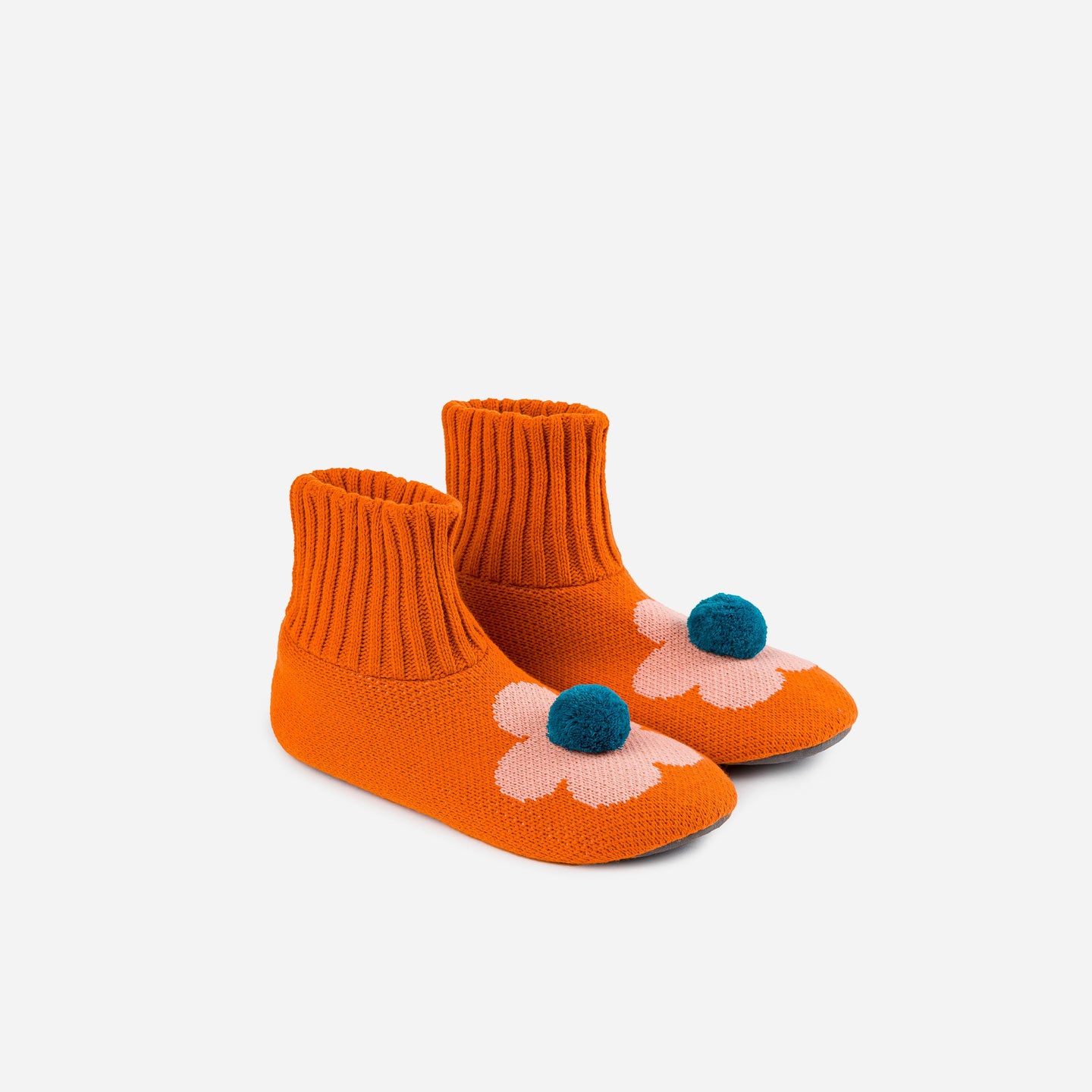 Orange non slip knit slippers with a pom on top