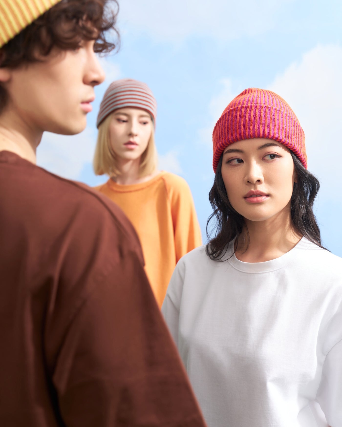 a collection of bright knit ribbed beanies on male and female models