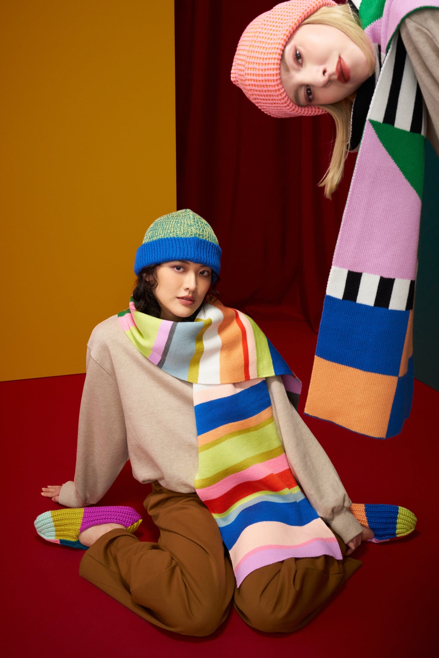 models wearing oversized graphic knit scarves and coordinating beanies